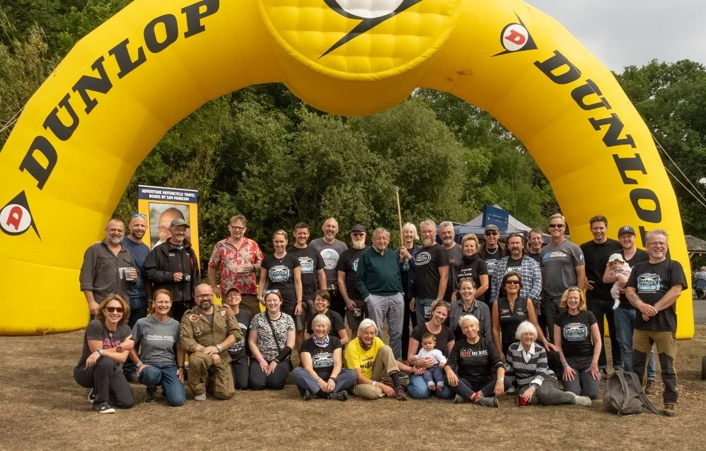 Group photo at the Overland Event Oxford 2022 under Dunlop arch — Markus André Mayer speaking alongside Ted Simon
