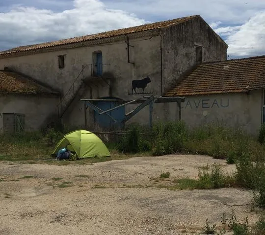 Green tent pitched on gravel car park of abandoned winery in the Camargue France 2016 — Markus Mayer stranded with broken Vespa