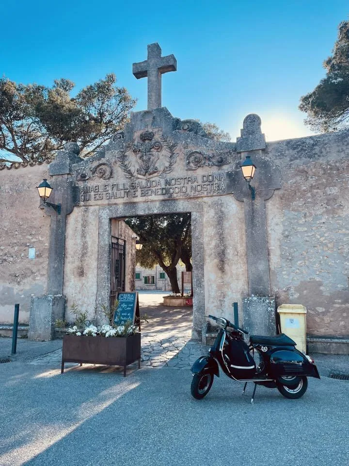 Valentina 1967 Vespa GS150 parked at the entrance of Santuari de Cura monastery Puig de Randa Mallorca — Vuelta Balearica 2026